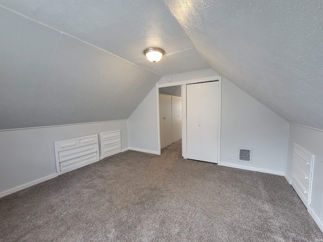 bonus room with lofted ceiling, a textured ceiling, visible vents, carpet floors, and baseboards