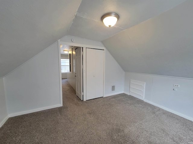 additional living space featuring baseboards, visible vents, carpet, and vaulted ceiling