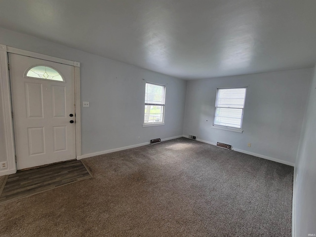 foyer with baseboards, dark colored carpet, and visible vents