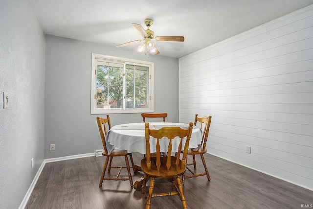 dining room with dark wood-type flooring, a ceiling fan, and baseboards