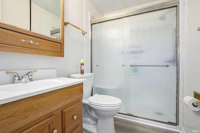 full bathroom featuring toilet, a shower stall, wood finished floors, and vanity