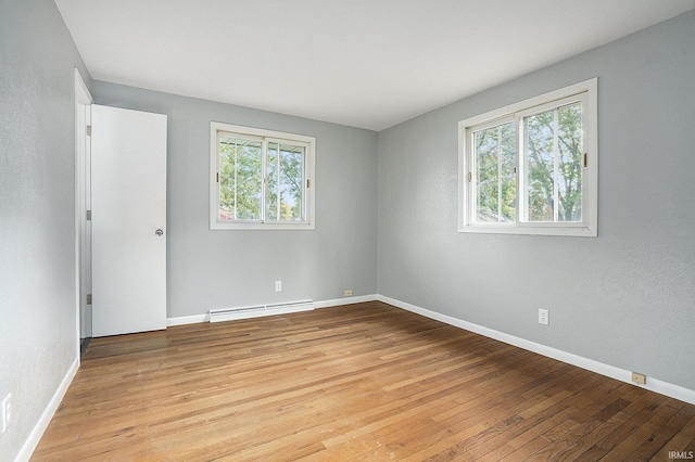 empty room featuring light wood-type flooring, a baseboard radiator, and baseboards