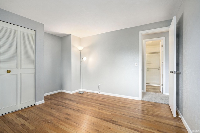 unfurnished bedroom featuring hardwood / wood-style floors, a closet, and baseboards