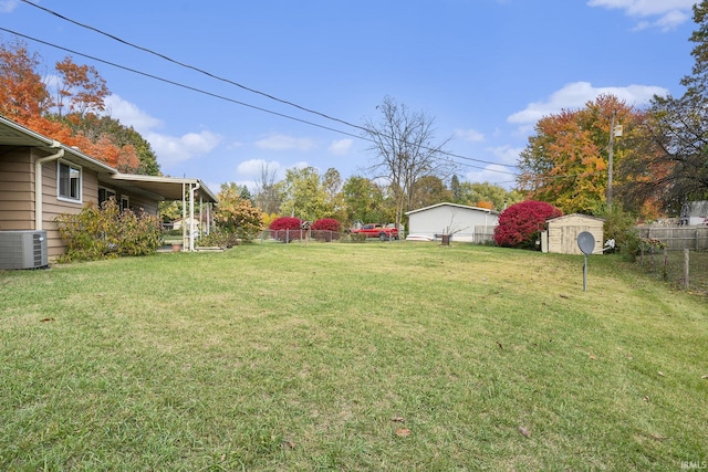 view of yard featuring a storage shed, fence, central AC, and an outbuilding