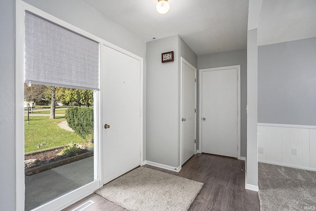 entryway with a wainscoted wall, visible vents, baseboards, and wood finished floors