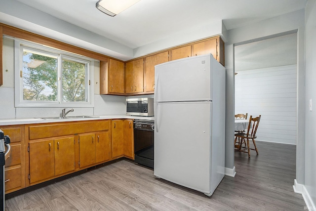 kitchen featuring light wood-style floors, black dishwasher, light countertops, freestanding refrigerator, and stainless steel microwave