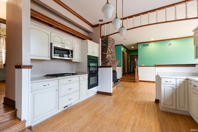 kitchen featuring crown molding, gas stovetop, stainless steel microwave, dobule oven black, and light wood-type flooring