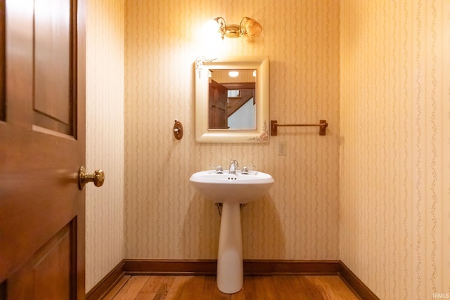 bathroom featuring wallpapered walls, baseboards, and wood finished floors