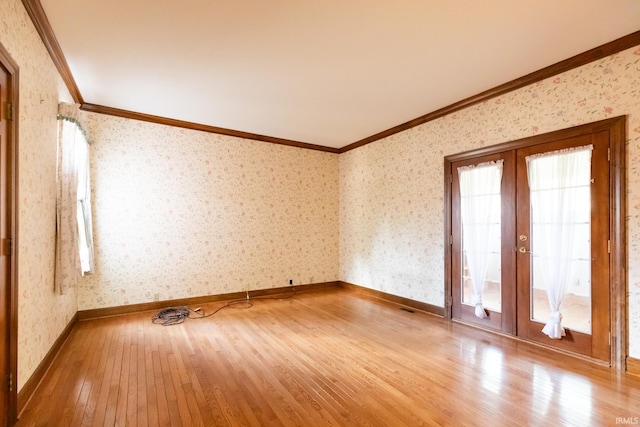 empty room with french doors, crown molding, hardwood / wood-style floors, and wallpapered walls