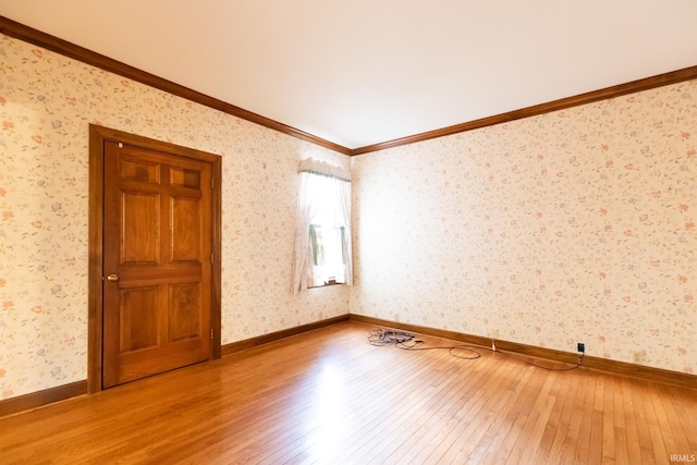 spare room with baseboards, ornamental molding, wood-type flooring, and wallpapered walls