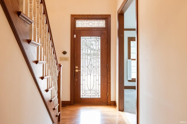 foyer entrance with stairs, light wood finished floors, and baseboards