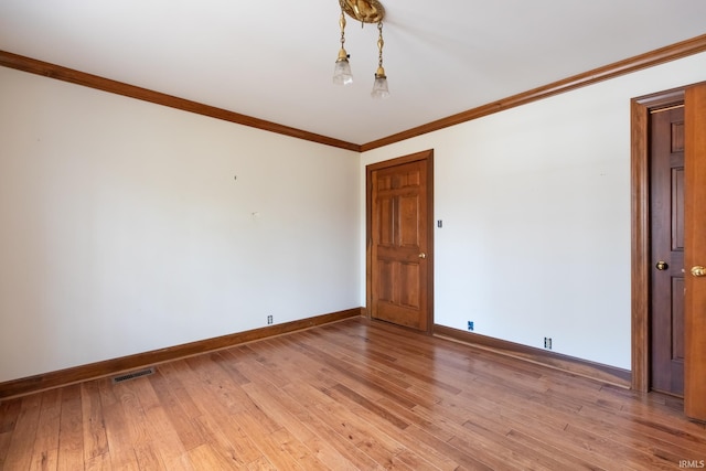 spare room featuring baseboards, light wood-style flooring, visible vents, and crown molding