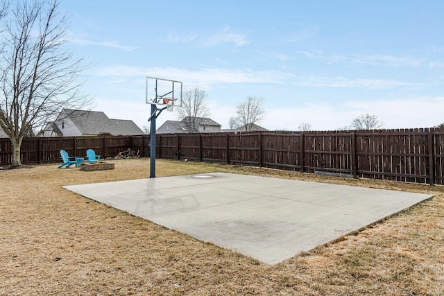 view of sport court with a fenced backyard, a yard, and basketball hoop