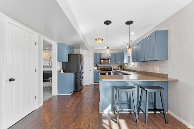 kitchen with blue cabinets, stainless steel appliances, a peninsula, tasteful backsplash, and dark wood finished floors