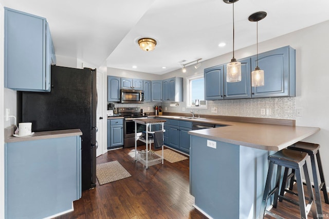 kitchen with dark wood finished floors, decorative backsplash, appliances with stainless steel finishes, blue cabinets, and a peninsula