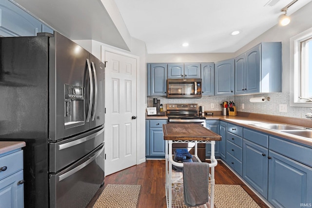 kitchen featuring decorative backsplash, dark wood finished floors, stainless steel appliances, blue cabinetry, and a sink