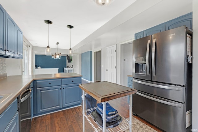 kitchen with blue cabinets, a peninsula, hanging light fixtures, appliances with stainless steel finishes, and dark wood finished floors