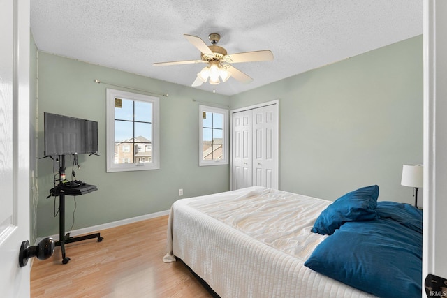 bedroom with a textured ceiling, a closet, wood finished floors, and baseboards