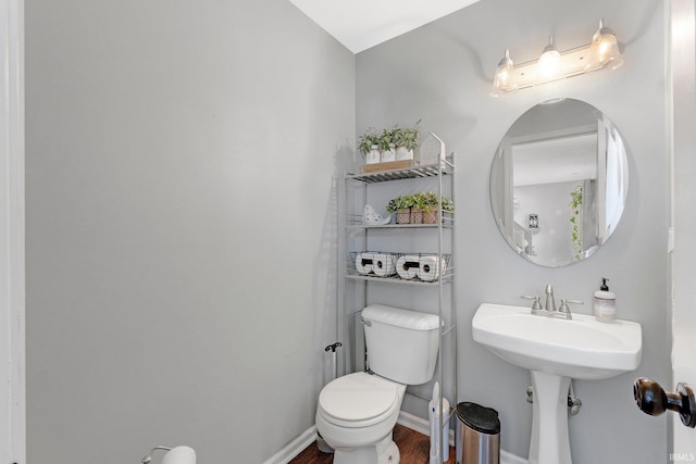 half bathroom featuring baseboards, toilet, and wood finished floors