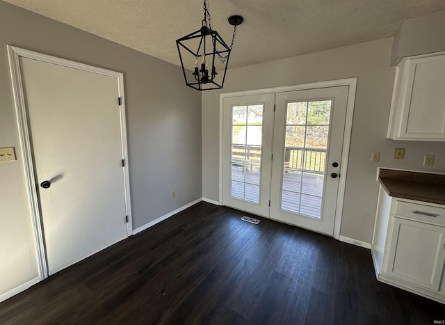 doorway featuring baseboards, visible vents, dark wood-type flooring, a textured ceiling, and a notable chandelier