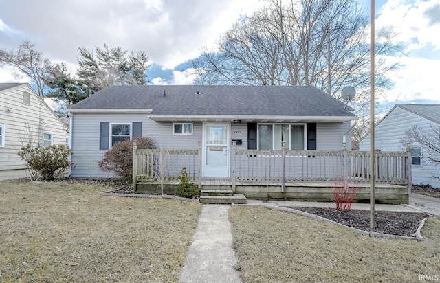 bungalow-style home with a shingled roof, covered porch, and a front lawn