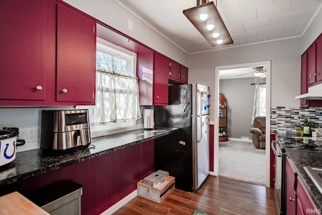 kitchen featuring dark countertops, appliances with stainless steel finishes, red cabinetry, ceiling fan, and under cabinet range hood