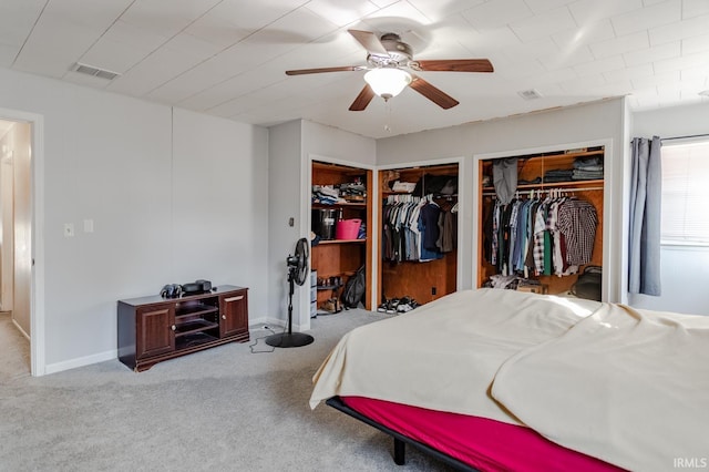 carpeted bedroom with ceiling fan, two closets, visible vents, and baseboards