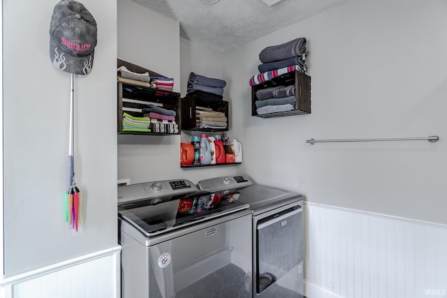 kitchen with a wainscoted wall, washer and clothes dryer, and a textured ceiling