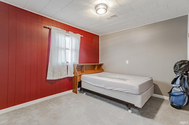 bedroom with wood walls, carpet, visible vents, and baseboards