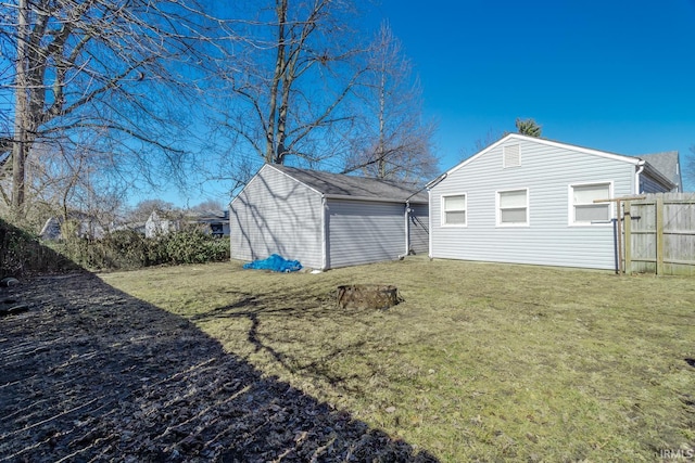 exterior space with a storage unit, fence, an outbuilding, and a yard