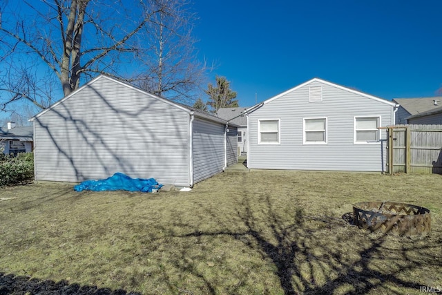 back of property featuring a yard, fence, and a fire pit