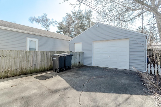 detached garage featuring aphalt driveway and fence