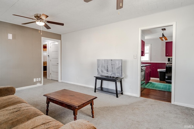 carpeted living area with ceiling fan and baseboards