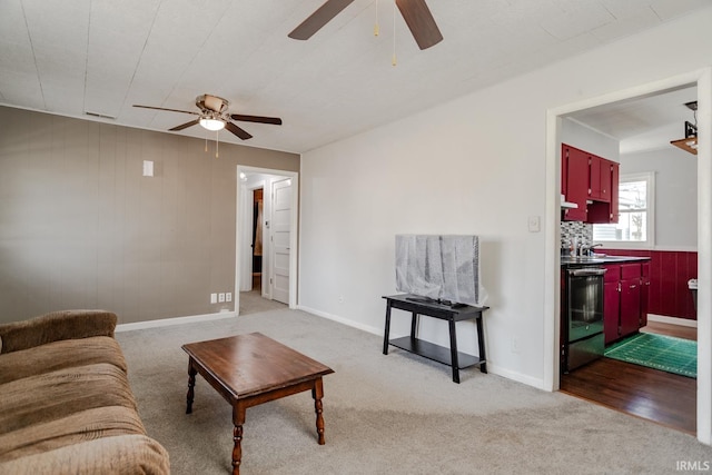 living room featuring light colored carpet, ceiling fan, and baseboards