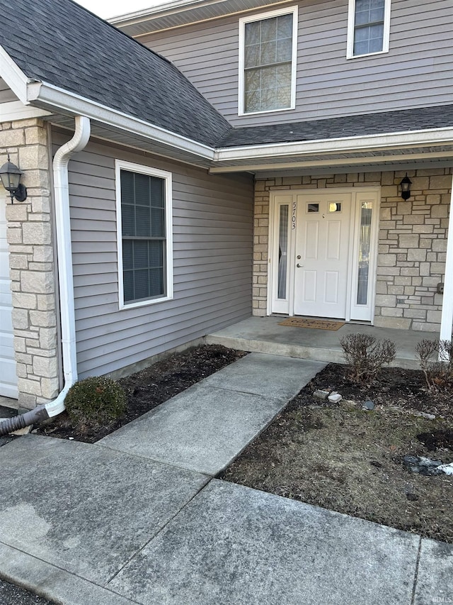 view of exterior entry featuring stone siding, roof with shingles, and covered porch