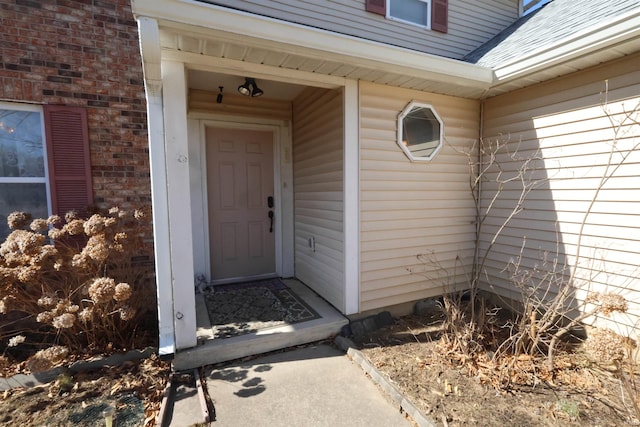 view of exterior entry featuring a shingled roof