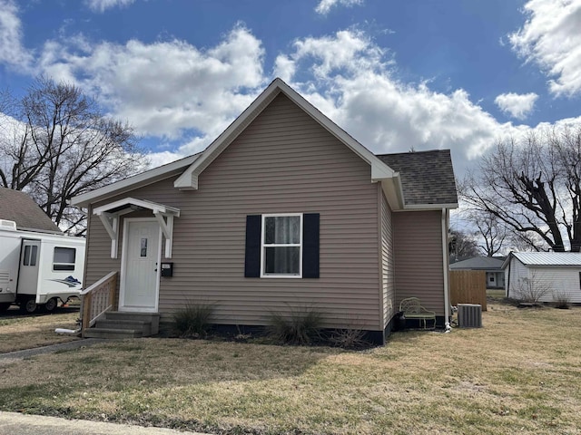 bungalow with entry steps, central AC, roof with shingles, and a front yard