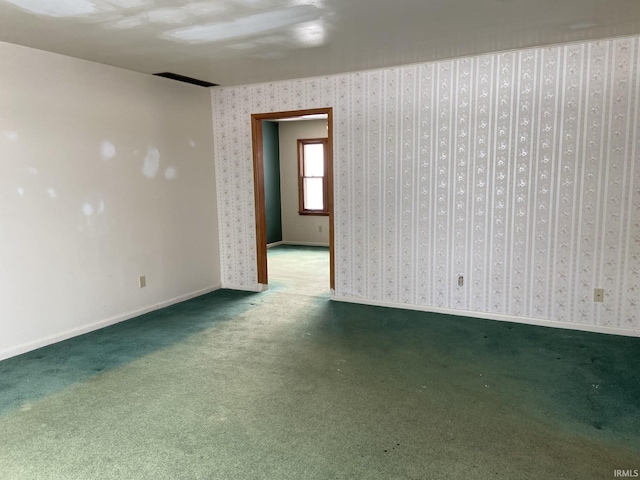 carpeted empty room featuring wallpapered walls and baseboards