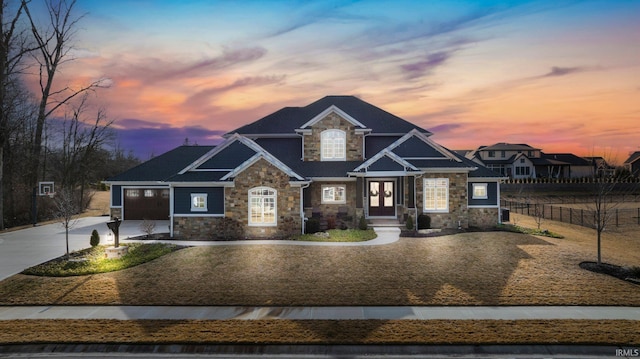 craftsman-style home featuring stone siding, fence, and concrete driveway