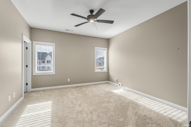 spare room with carpet floors, a ceiling fan, visible vents, and baseboards