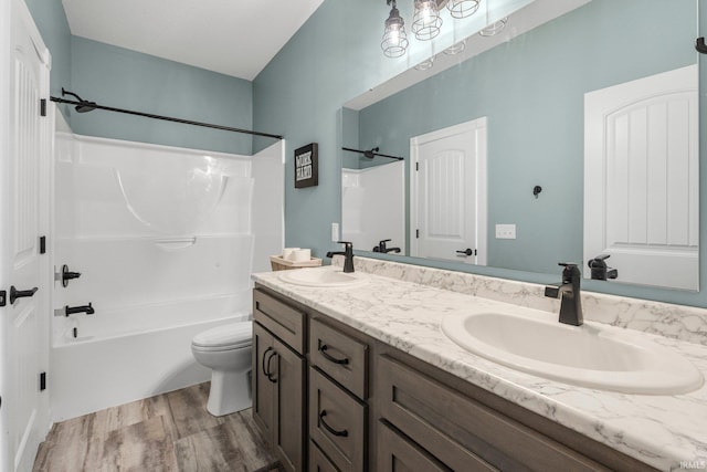 full bath with toilet, shower / washtub combination, a sink, and wood finished floors