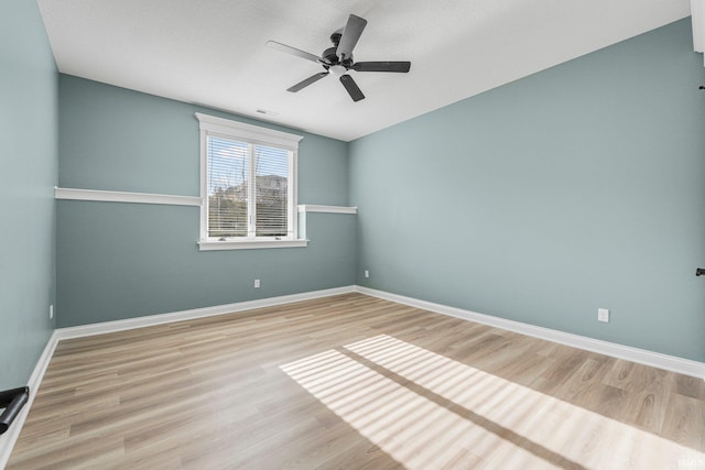 empty room featuring wood finished floors, a ceiling fan, and baseboards