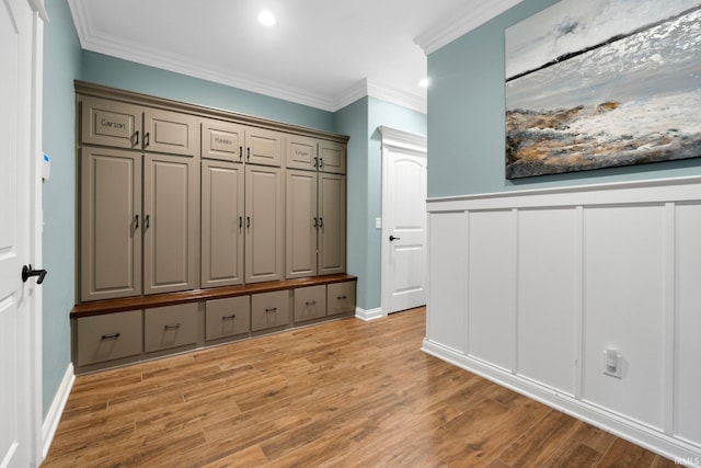 mudroom with light wood finished floors, ornamental molding, recessed lighting, and a decorative wall