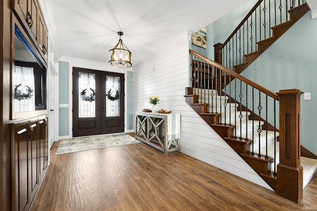 entrance foyer featuring a chandelier, wood finished floors, french doors, stairway, and crown molding