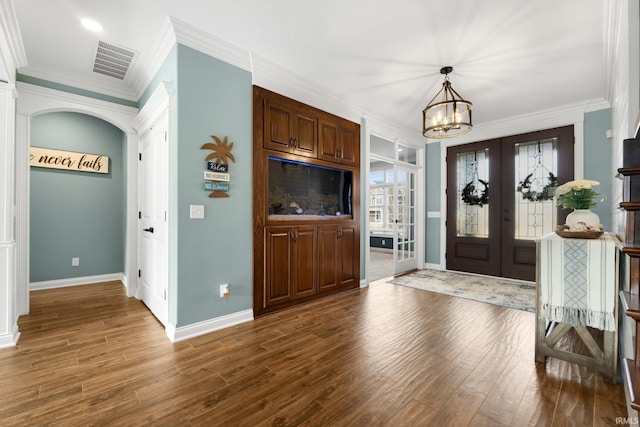 foyer with baseboards, dark wood-style flooring, visible vents, and crown molding