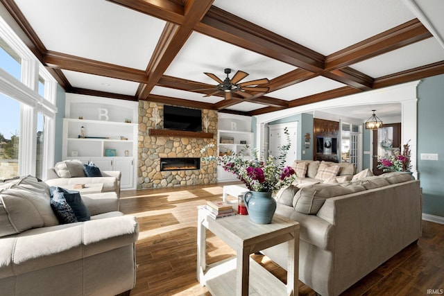 living area featuring built in shelves, beam ceiling, a stone fireplace, wood finished floors, and coffered ceiling