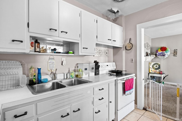 kitchen with light tile patterned floors, a sink, white cabinets, electric stove, and light countertops