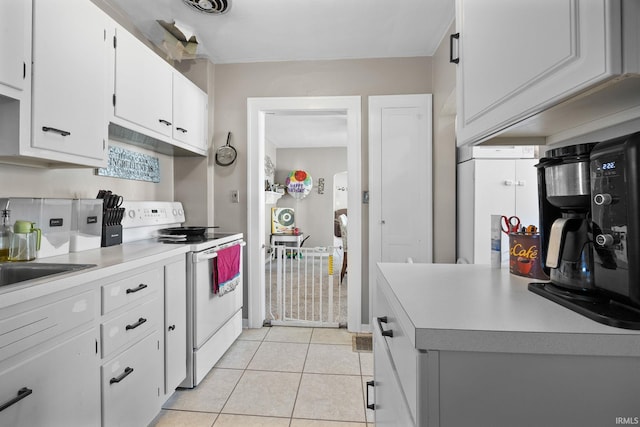 kitchen featuring light tile patterned floors, light countertops, white electric range oven, and white cabinets