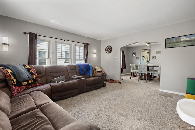 carpeted living area with baseboards and arched walkways