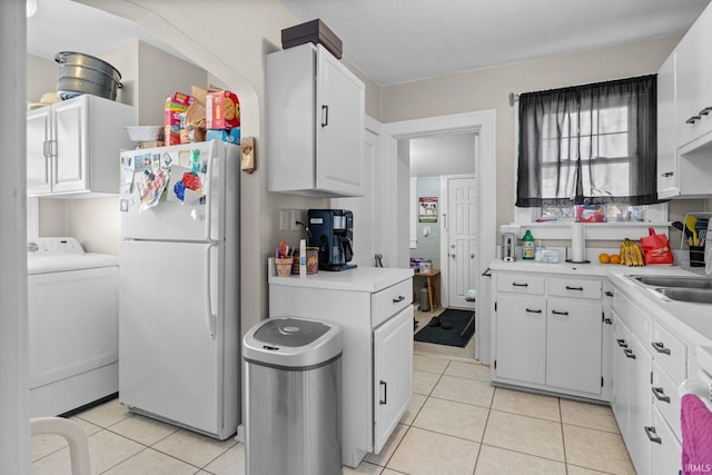 kitchen featuring light countertops, washer / clothes dryer, light tile patterned flooring, and freestanding refrigerator